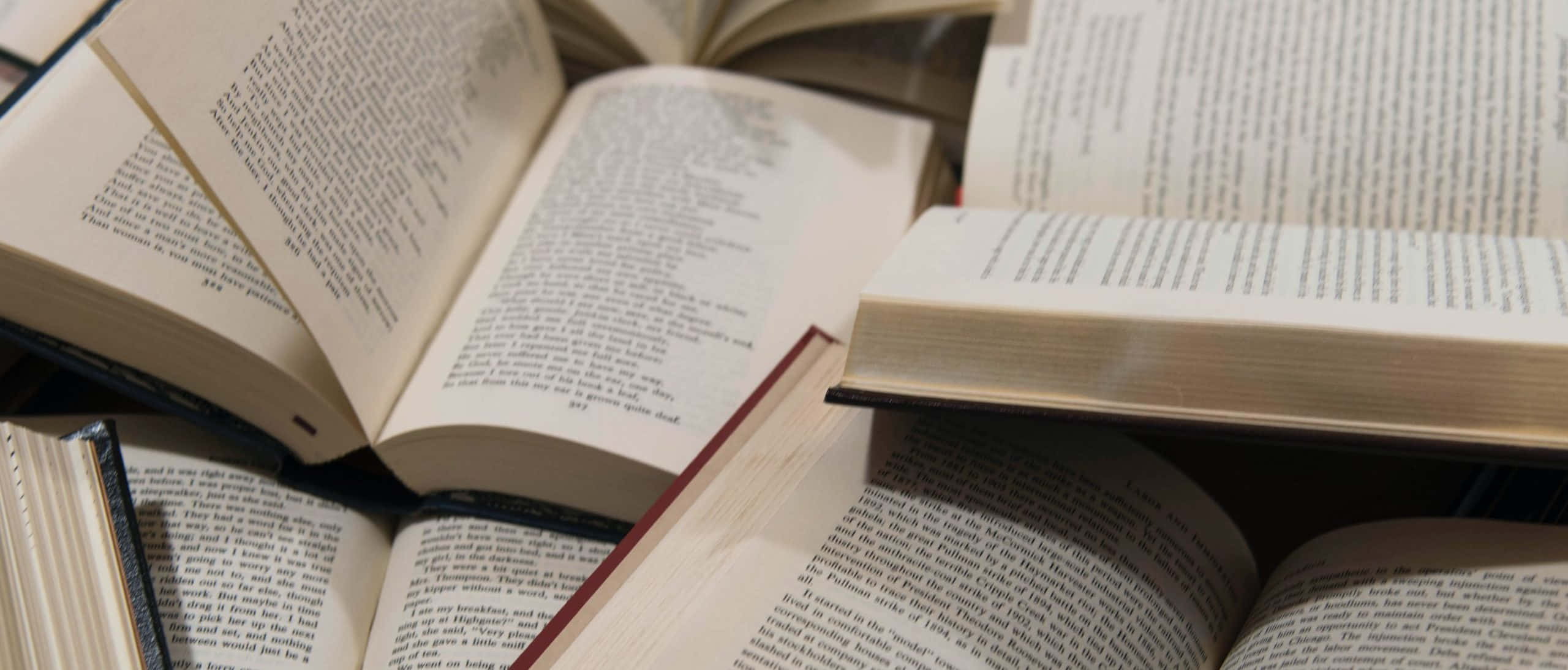 انبوهی از کتاب‌ها روی میز والپیپر