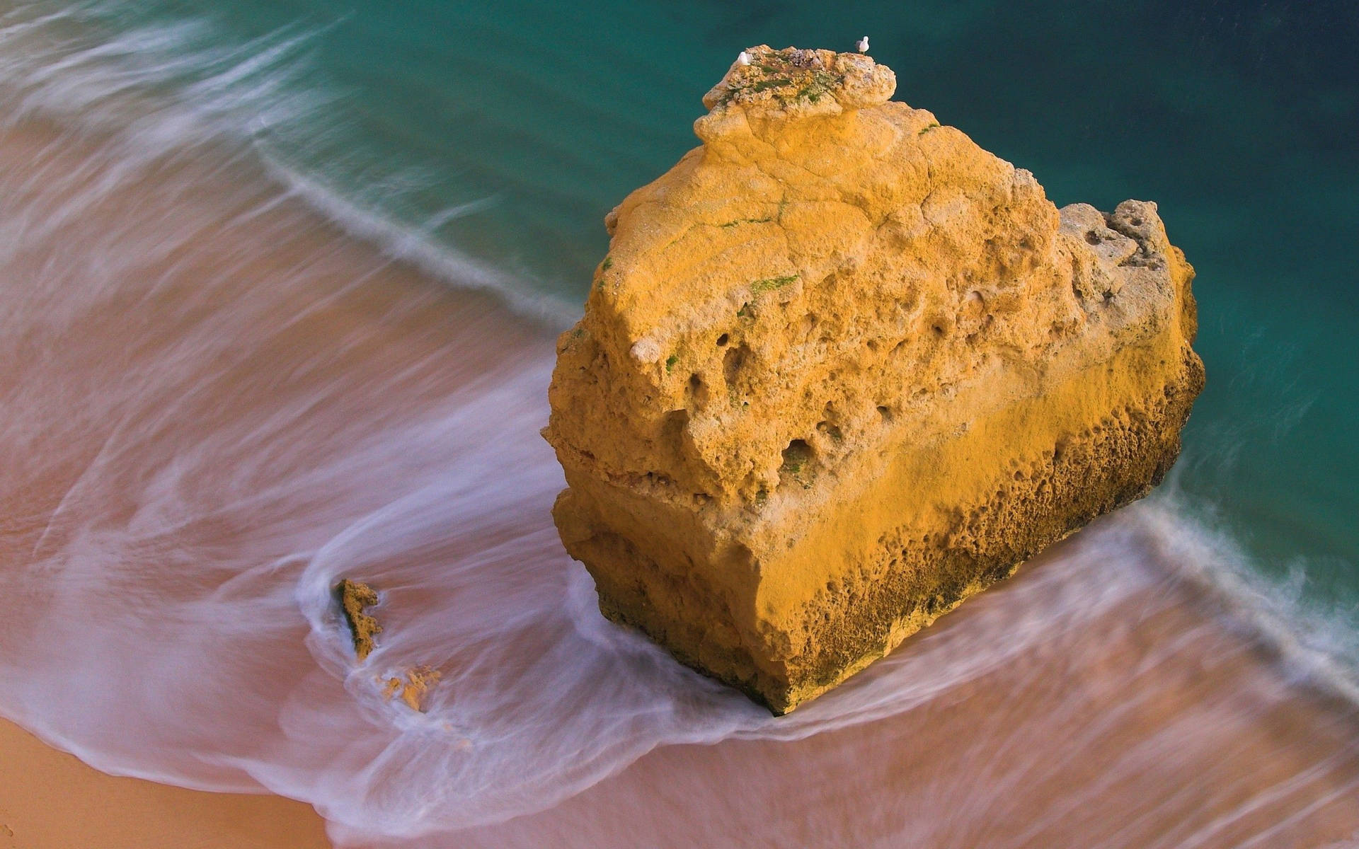 اقیانوس با صخره بزرگ زرد روی ساحل یا ماسه و امواج سفید
