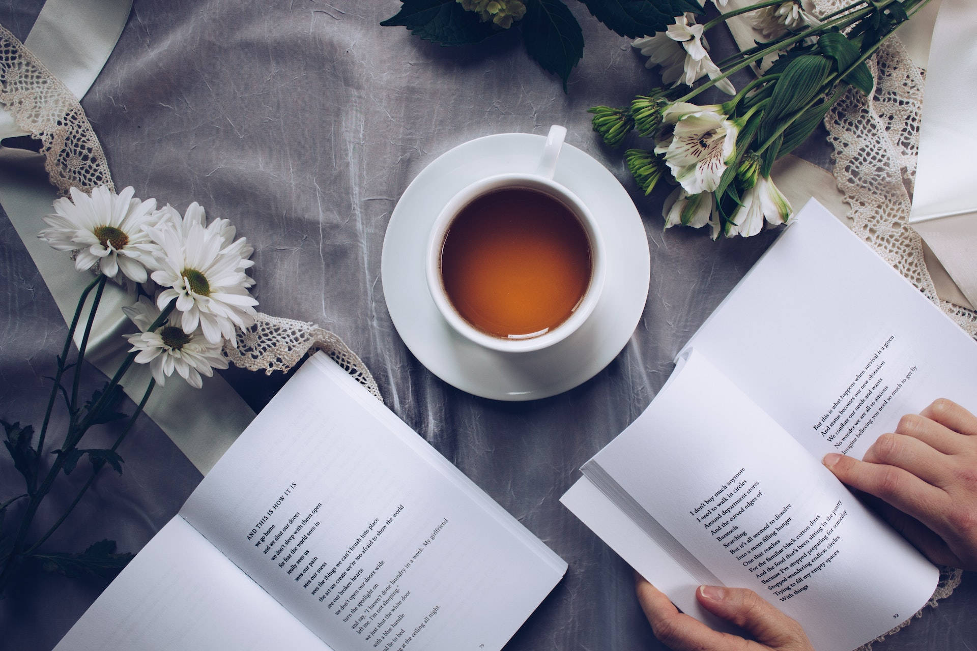 فنجان چینی سفید با نعلبکی در کنار دو کتاب والپیپر