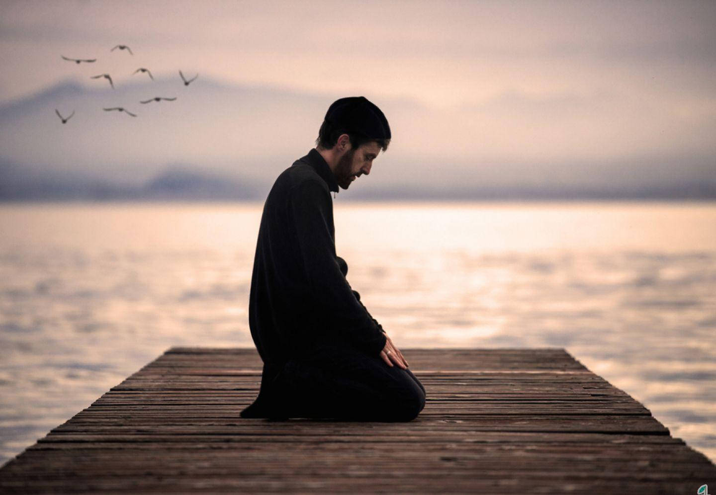 مرد نمازگزار زانو زده روی اسکله والپیپر