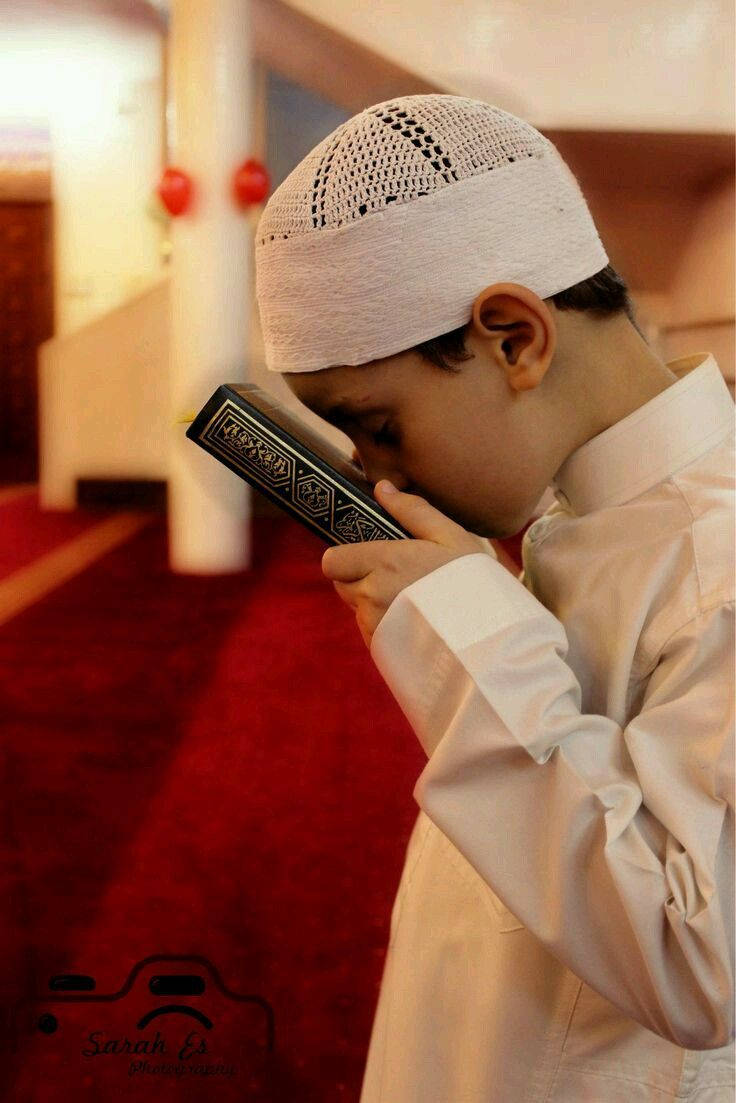 پسر مسلمان در حال بوسیدن قرآن والپیپر