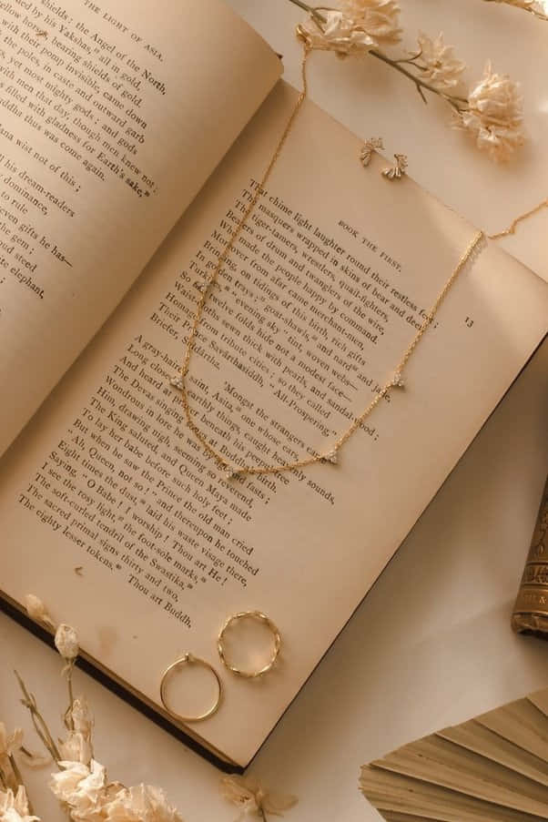 کتابی با گردنبند و انگشتر روی آن والپیپر