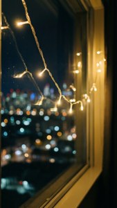 چراغ‌های پری کنار پنجره با بوکه شهری در شب. — کریسمس زیبا والپیپر